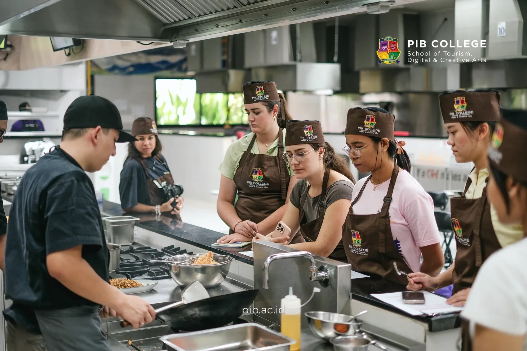 Chef demonstrating the first cooking steps to students at a kitchen island