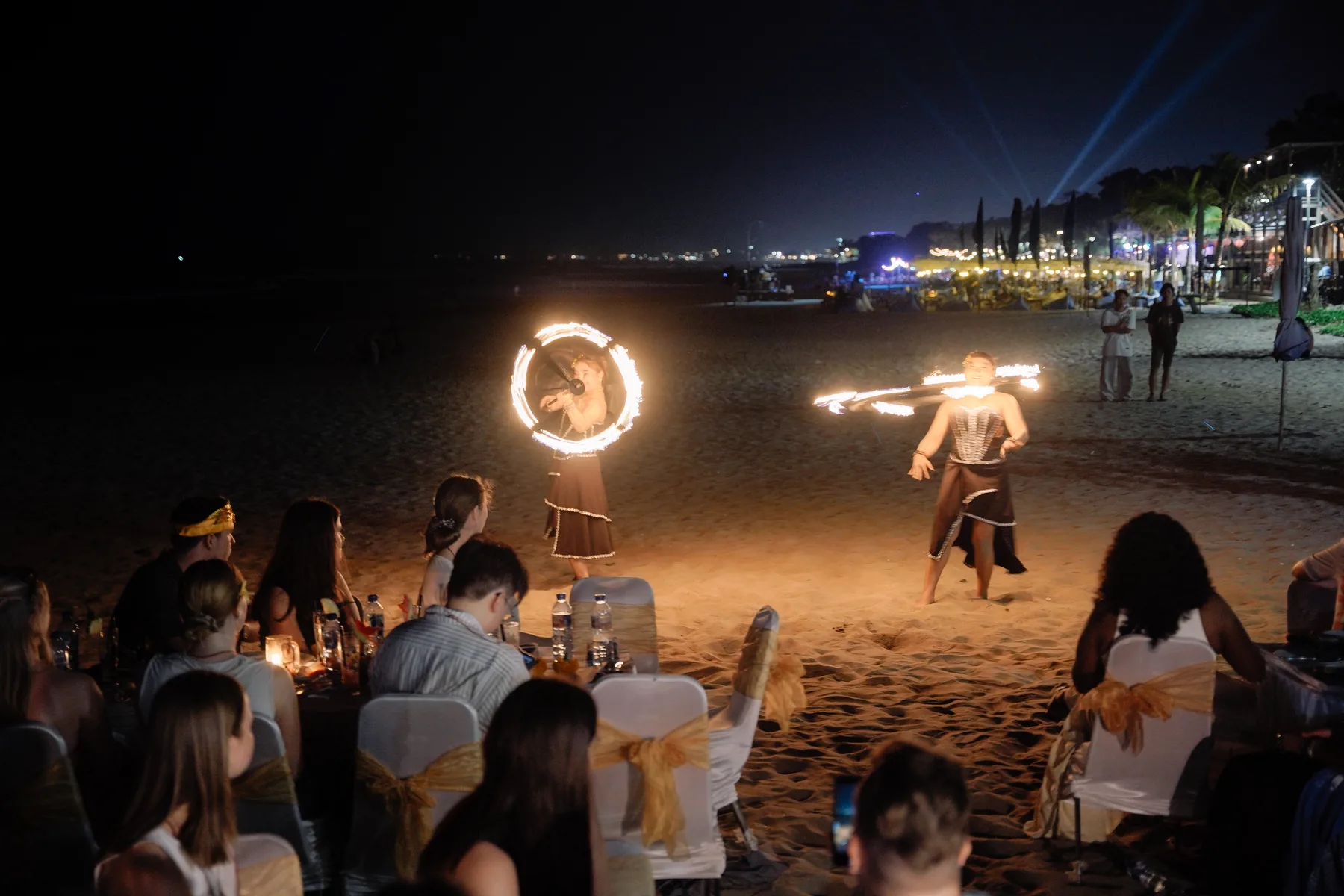 Two fire dancers performing on the beach in front of the dinner tables at the Welcoming Dinner