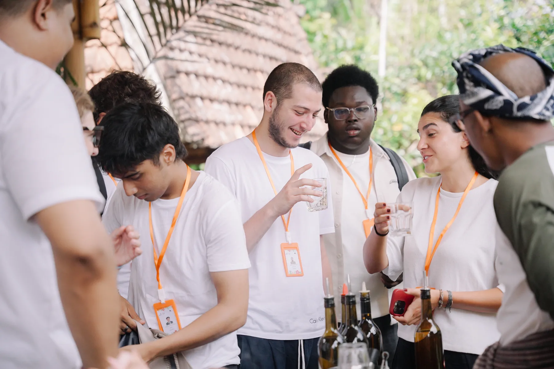 A group of students with orientation lanyards talking and laughing under a tiled roof at Omah Blumbungan