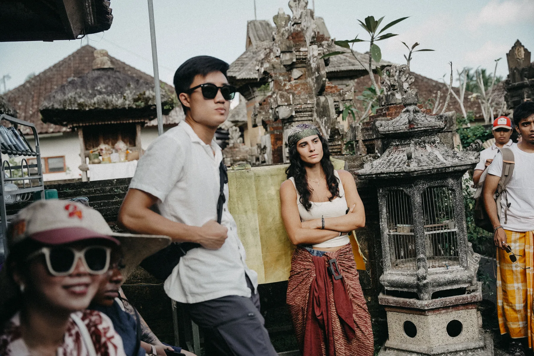 Students standing among carved stone shrines at a temple complex during the Goa Gajah and Penglipuran excursion