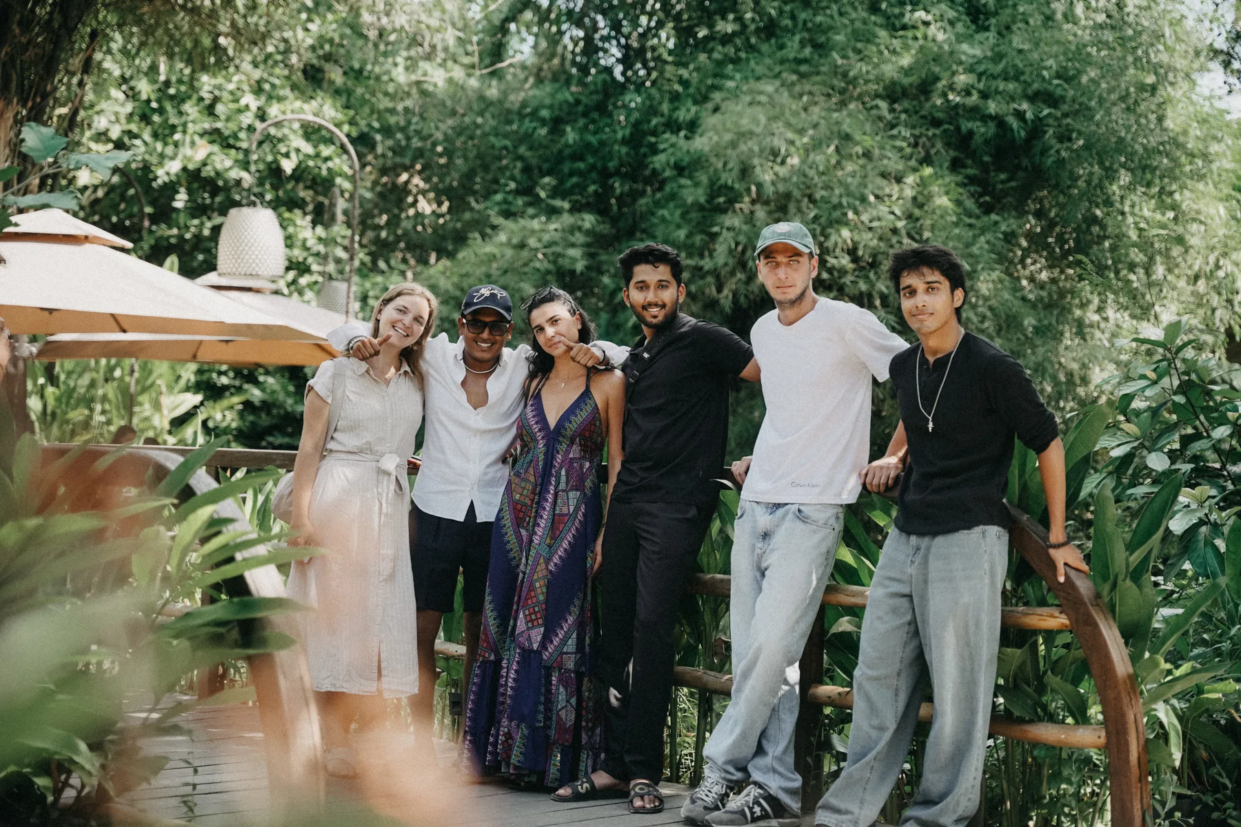 A group of students posing together on a wooden bridge in the gardens of the Nuanu and Ulaman resort