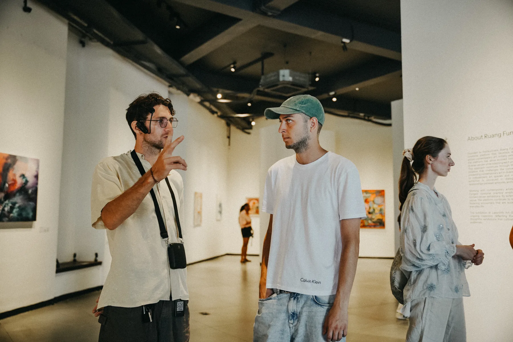 Students talking in an art gallery at Nuanu, paintings on the white walls around them