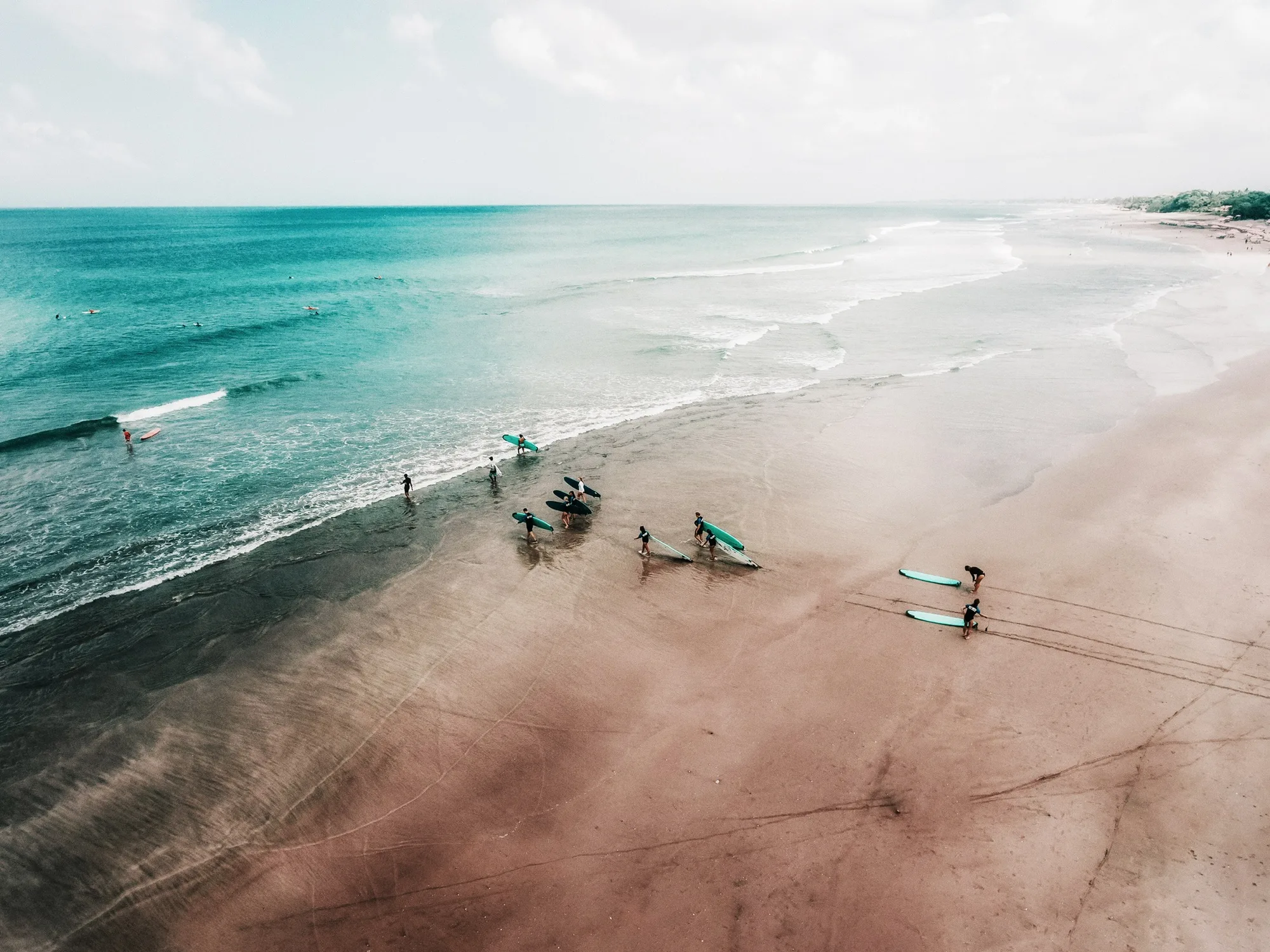 Surfers on a Bali beach from above