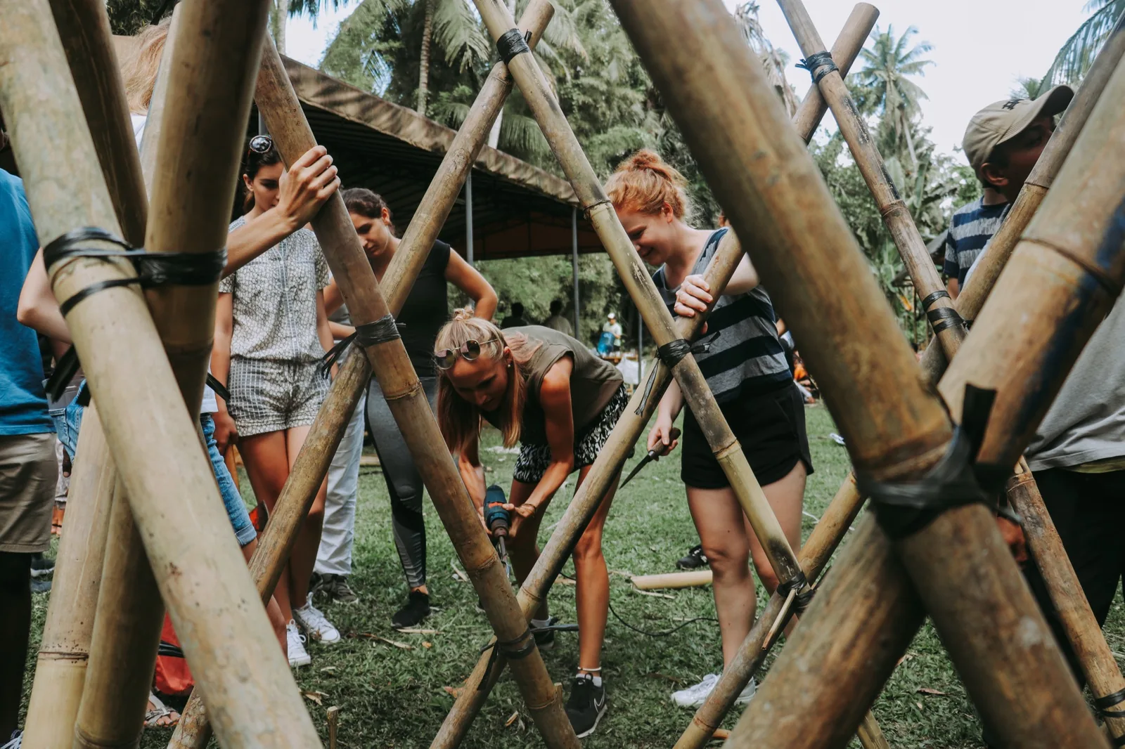 Students building inside a bamboo lattice structure at a construction workshop