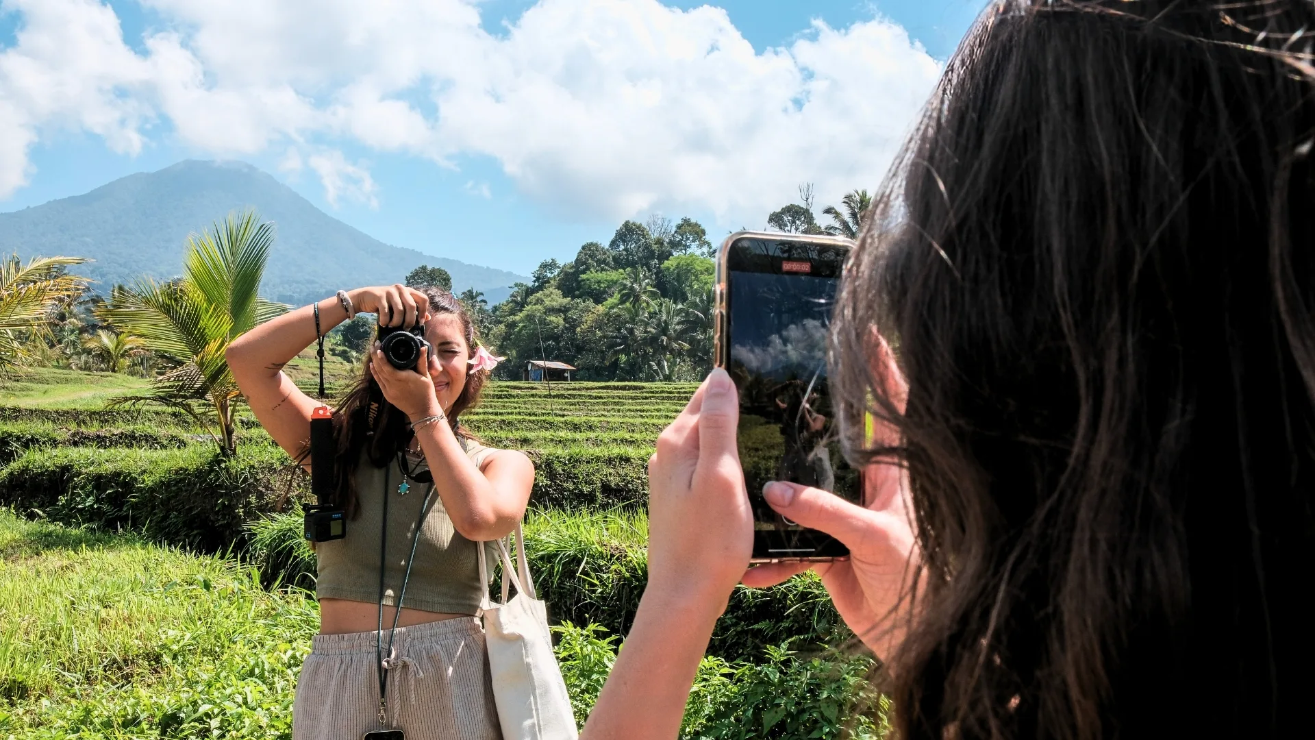 Student photographing at Bali rice terraces with a volcano in the background