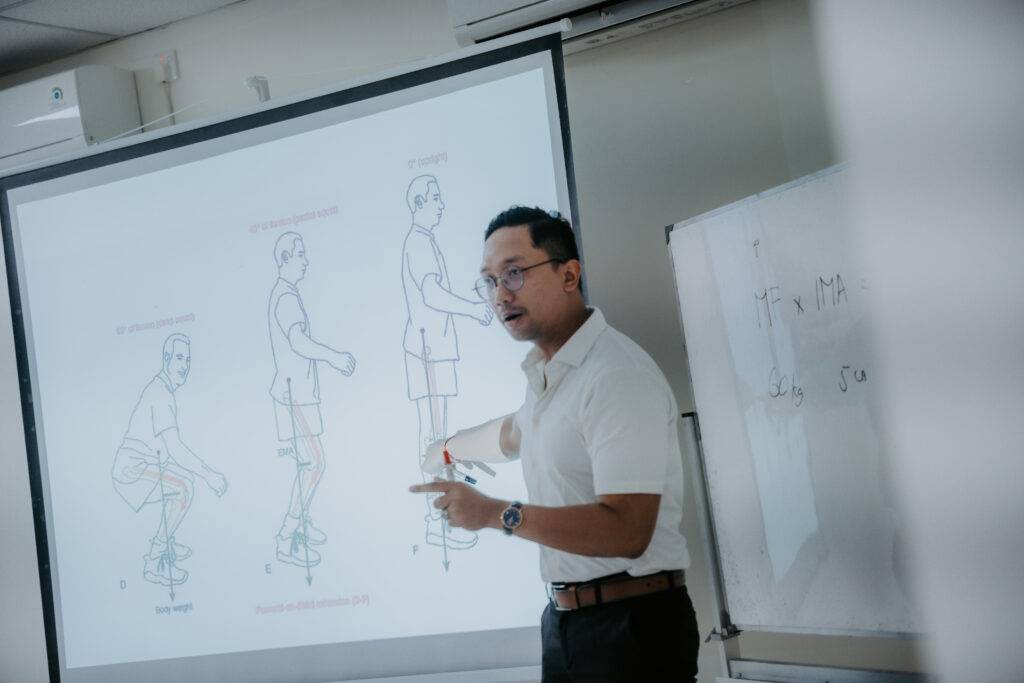 Mr. Partha teaching Sports and Physiotherapy Program students in a classroom at Universitas Udayana, Bali.