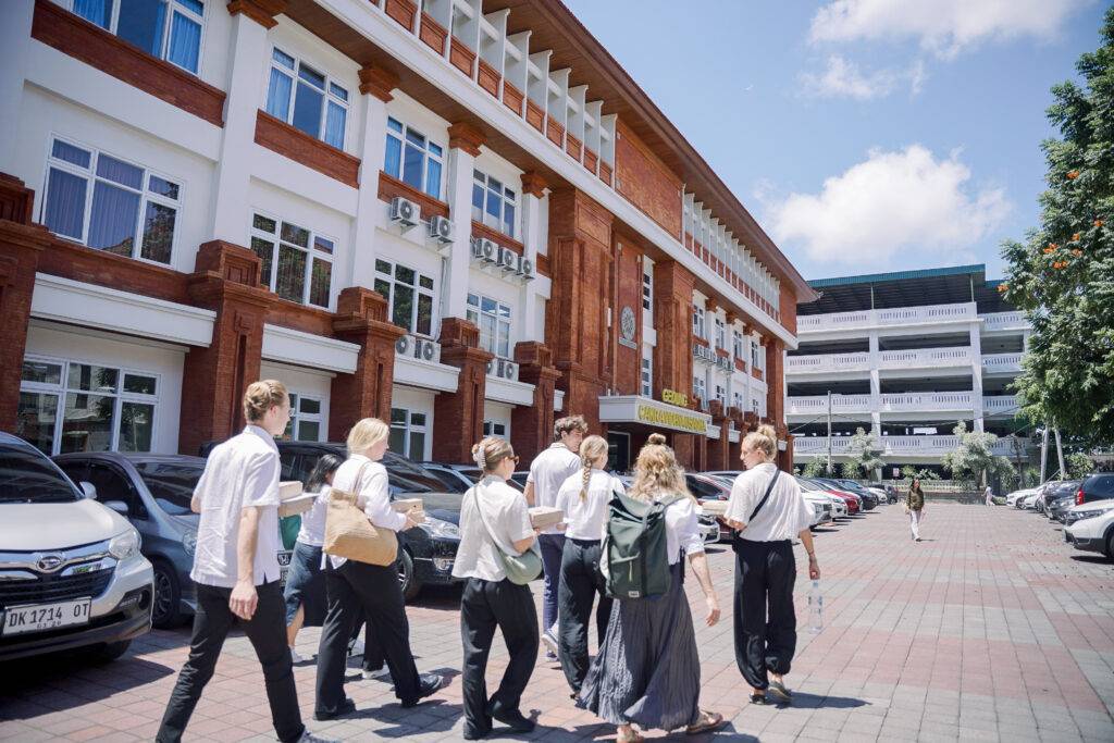 Students from the Universitas Udayana (UNUD) study abroad programs walking together on the Sudirman Campus, exploring the vibrant academic environment.